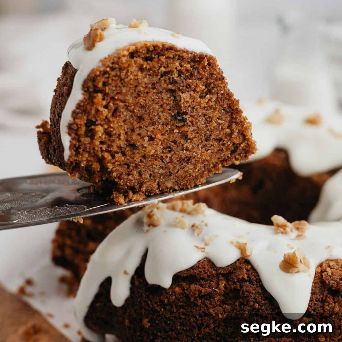 A slice of carrot bundt cake being lifted with a silver cake server.