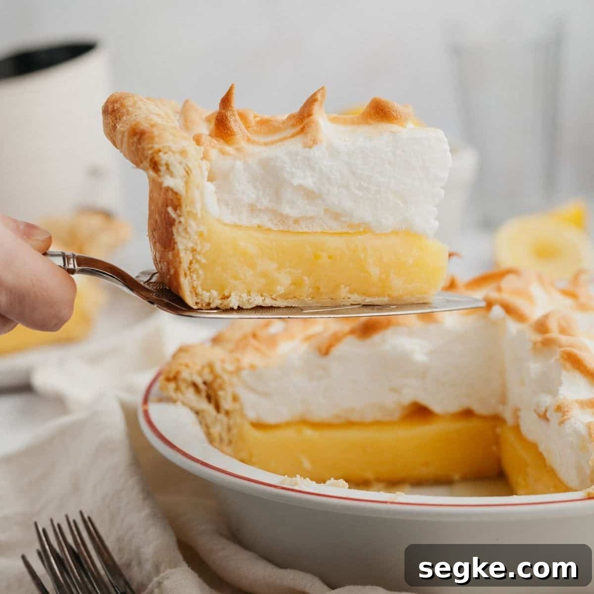 a slice of lemon meringue pie being lifted out with a serving knife.