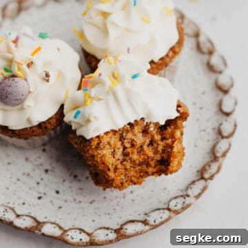 A small plate with three carrot cupcakes, one has a bite taken out of it.