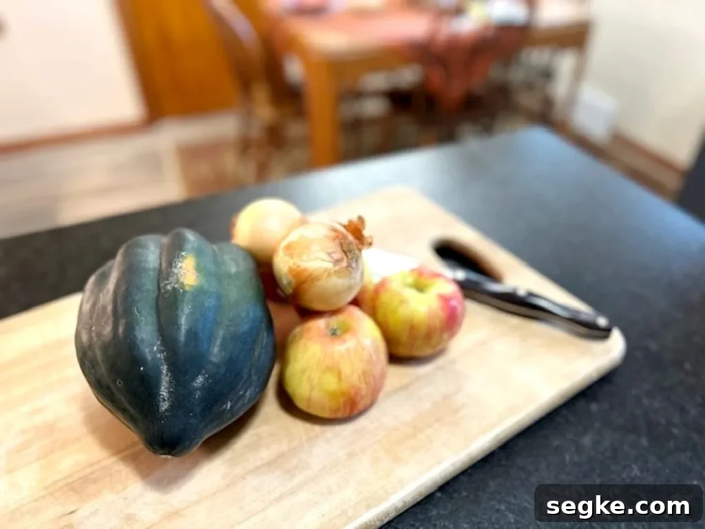 Whole acorn squash and fresh apples on a wooden cutting board, ready for roasting — simple ingredients for a cozy fall side.