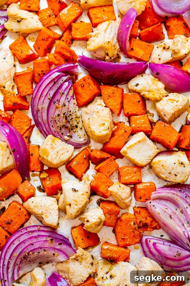 Sheet Pan Chicken with Roasted Sweet Potatoes 2 red onion, chicken and sweet potato cubes on a baking tray.