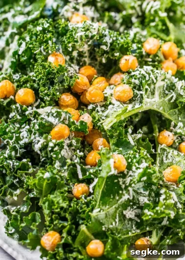 A plate of kale salad topped with roasted chickpeas and grated cheese.