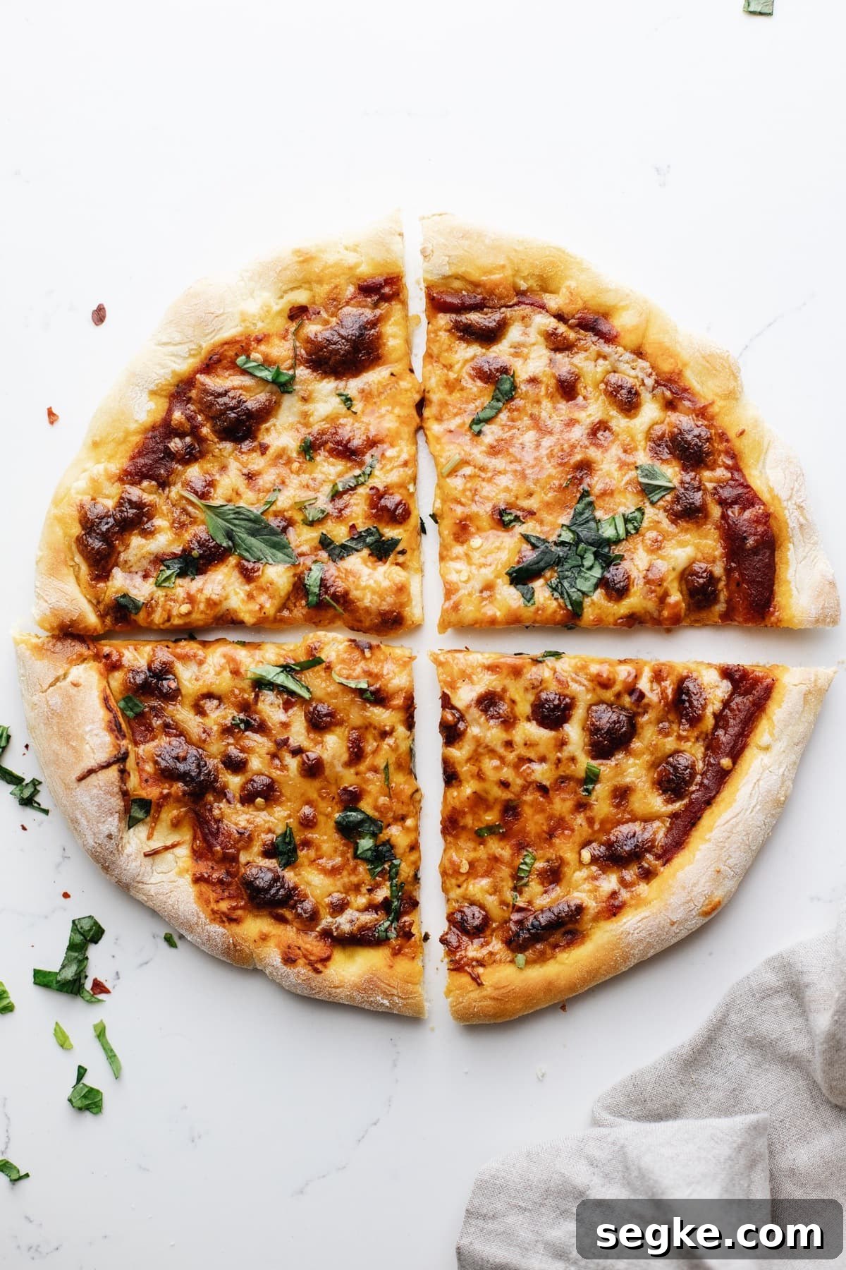 How to Make Crispy Cast Iron Skillet Pizza 9 A cast iron skillet pizza on a white counter top cut into 4 slices.