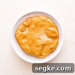 elephant ears pastry dipped in cinnamon sugar in a white bowl.