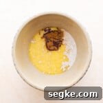 butter cinnamon and salt added to yeast mixture for elephant ears pastry in a ceramic bowl.
