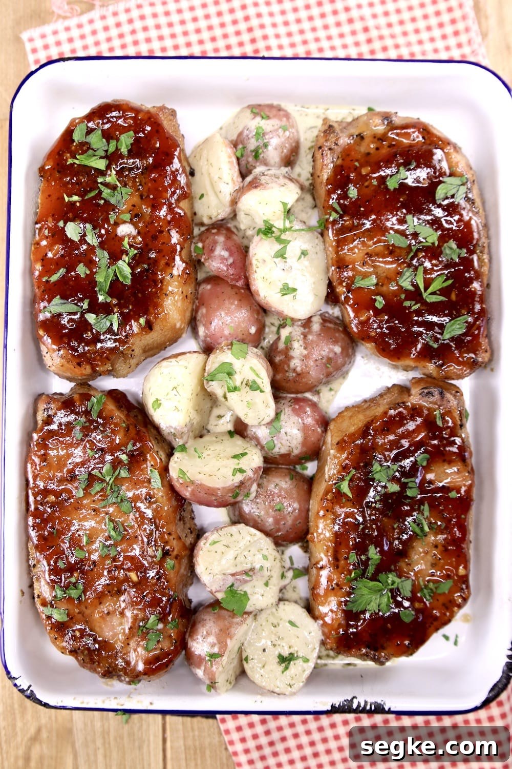Pan of grilled pork chops with bbq sauce and red potatoes down the center