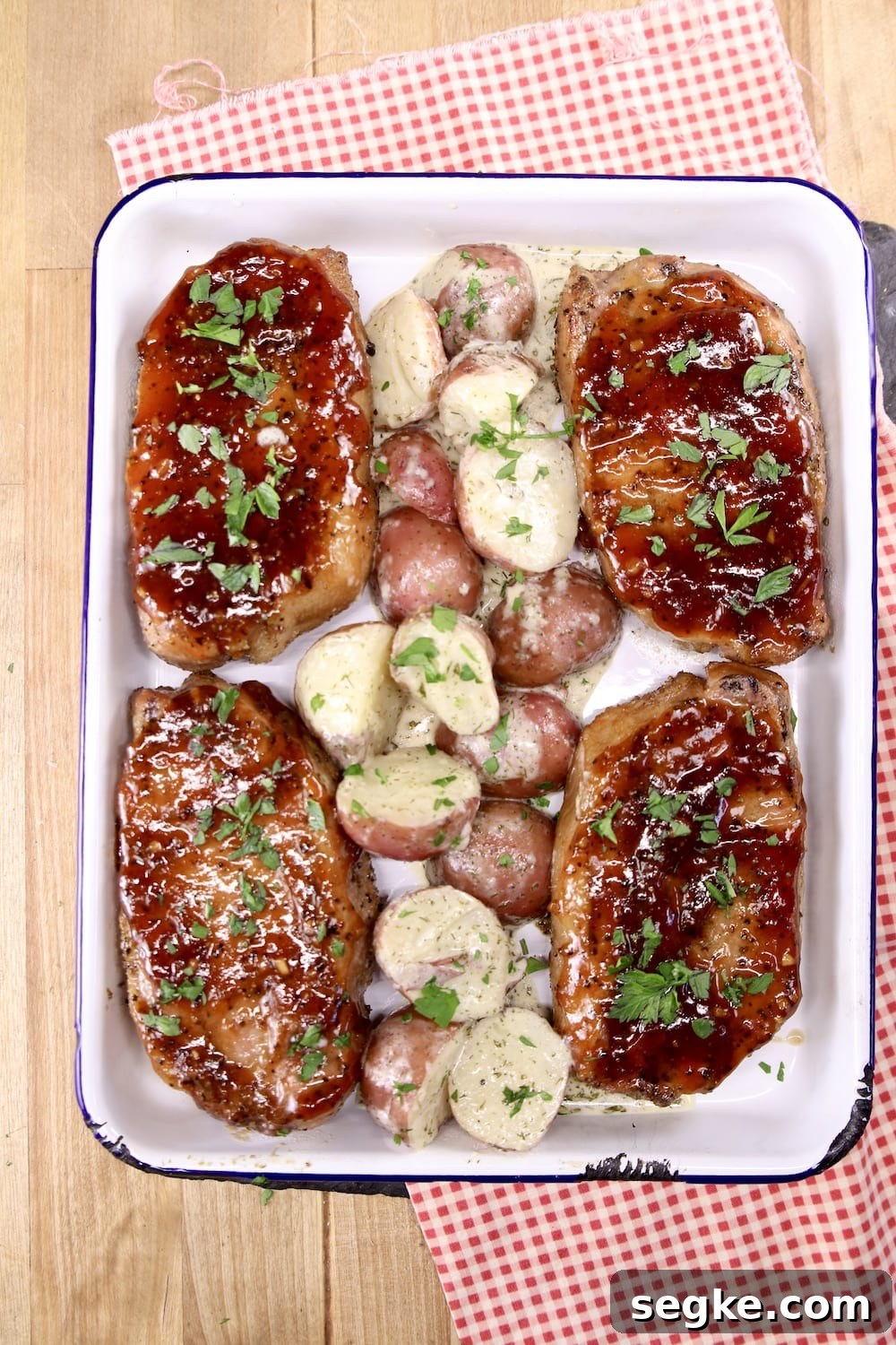 Pan of 4 bbq pork chops with red potatoes in center