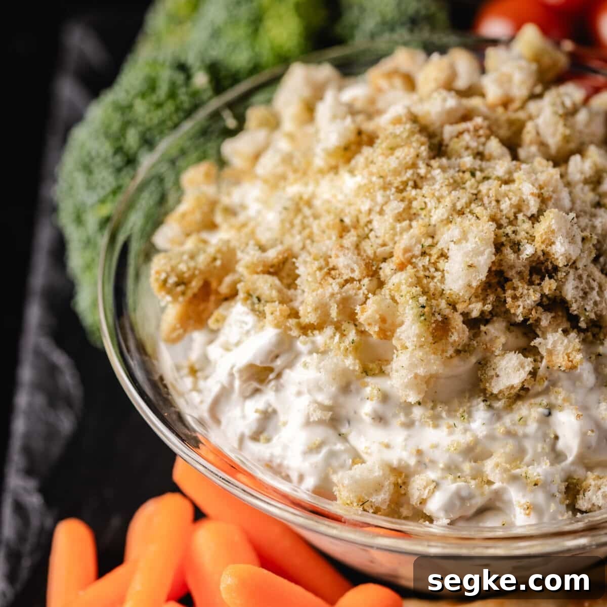 5 Game Day Dip Recipes Your Guests Will Love 7 A closeup shot of a bowl of dip next to carrot sticks and broccoli.