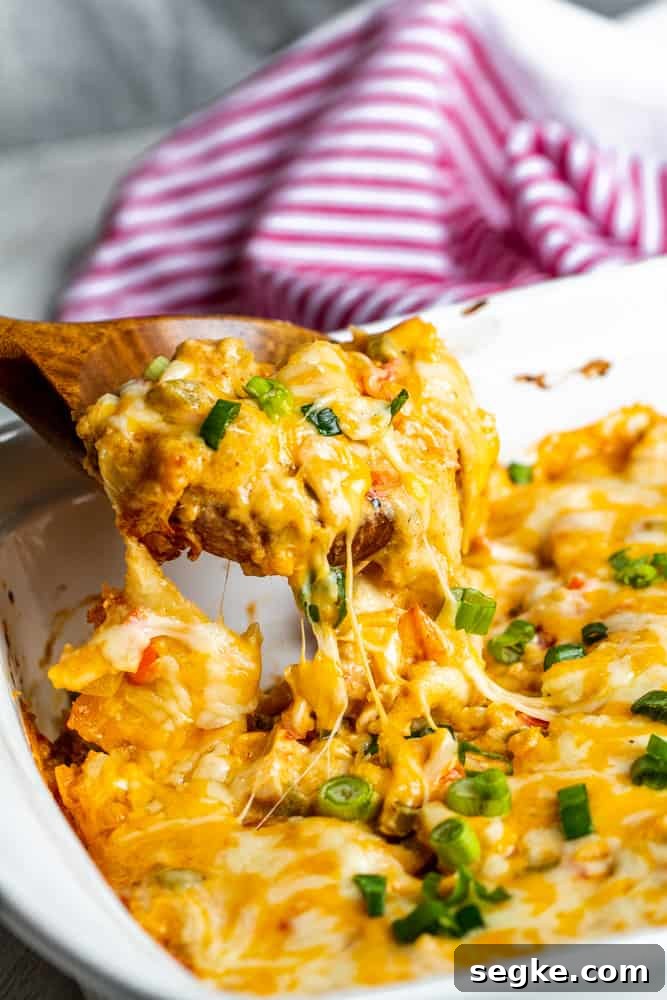 Creamy King Ranch Chicken Casserole Recipe 6 Casserole being lifted out of baking dish with wooden spoon.