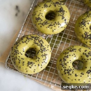 baked matcha doughnuts topped with black sesame seeds on wire cooling rack