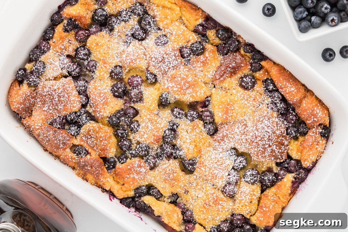 A French toast casserole garnished with blueberries and powdered sugar.