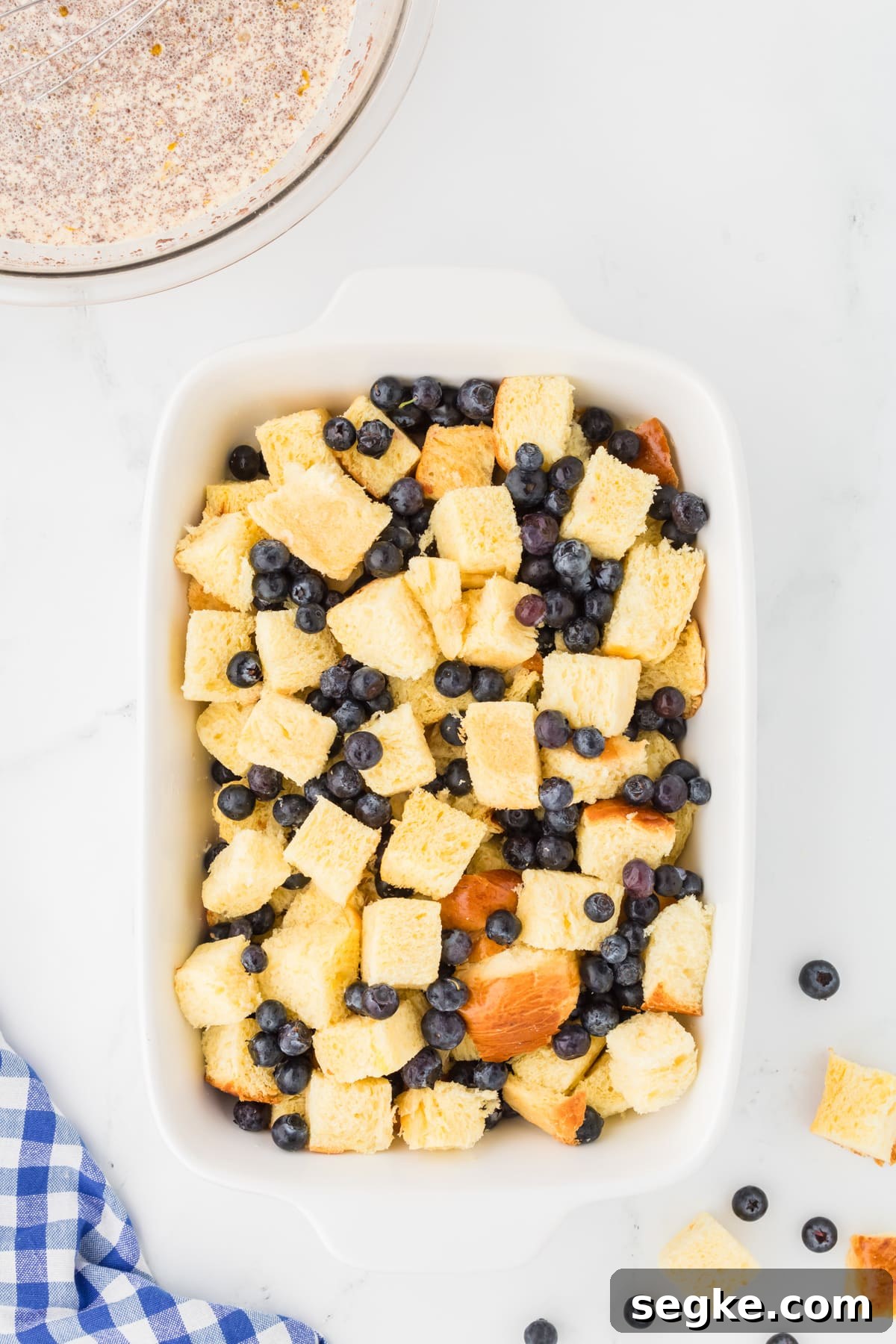 A baking dish filled with brioche cubes and blueberries.