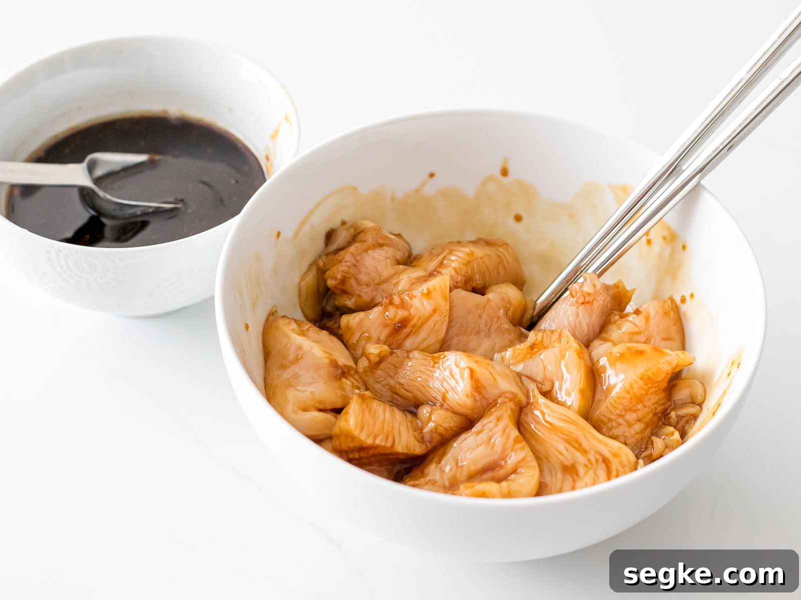 chicken breast mixed with soy marinade in a white bowl