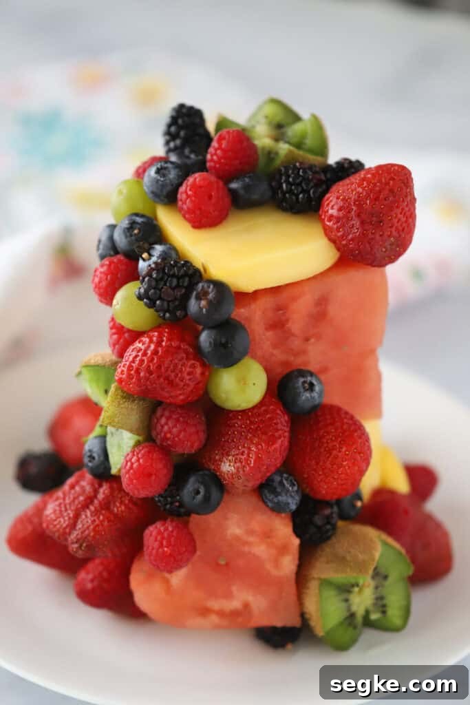 A plate with a cake made out of fruit, starting with a watermelon base and smaller berries and kiwis to decorate around the edge.