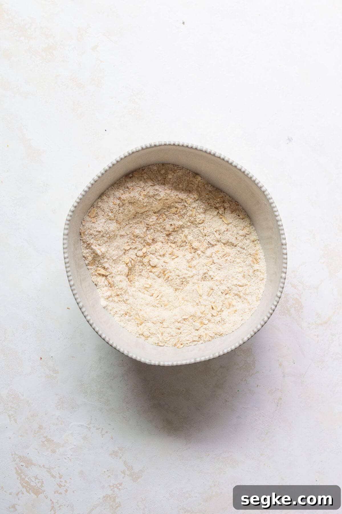 Dry ingredients for gluten-free chocolate chip oatmeal muffins whisked together in a large mixing bowl.