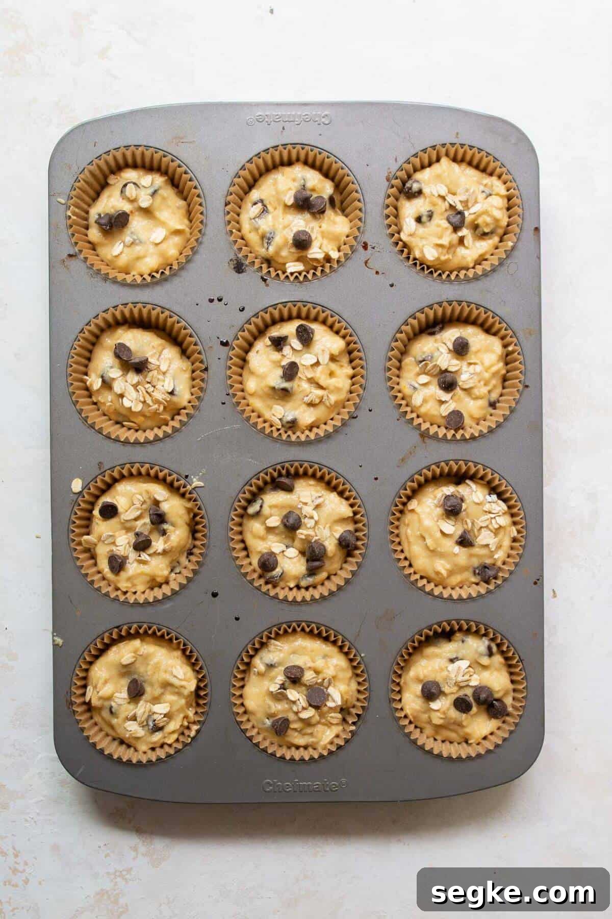 Healthy chocolate chip oatmeal muffin batter divided evenly in a lined muffin tin ready to bake.