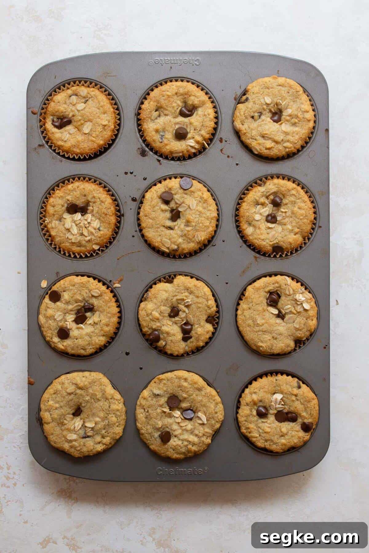 Freshly baked gluten-free chocolate chip oatmeal muffins cooling in a muffin tin.