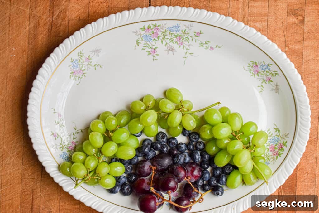 Green grapes are added to the platter with the blueberries and grapes.