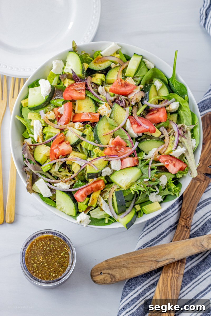 large green salad in a white bowl with a small glass jar of vinaigrette next to it