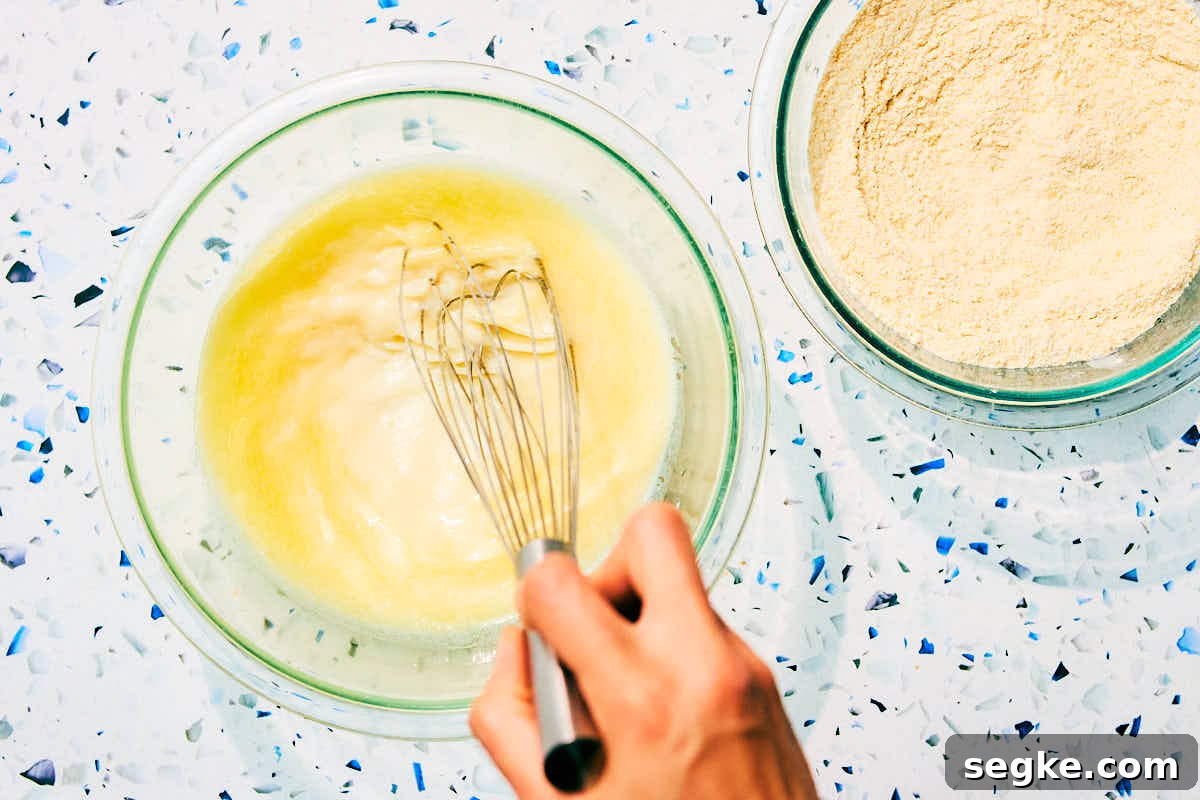 Wet and dry ingredients being whisked in separate bowls for cornbread.