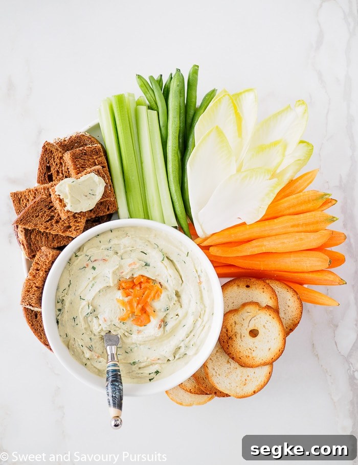 Smoked Salmon and Cream Cheese Dip 5 Top view of a bowl of Smoked Salmon and Cream Cheese Dip served with vegetables, pumpernickel bread and crackers.