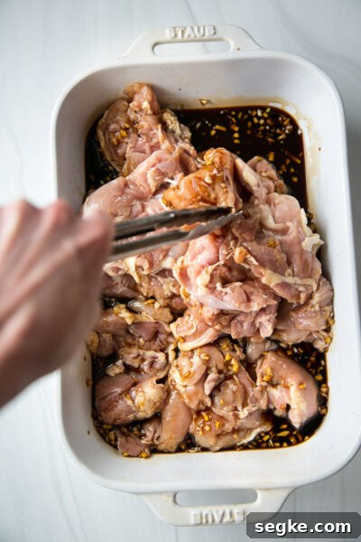 Homemade 5-Ingredient Gluten-Free Teriyaki Sauce and Marinade 5 tongs tossing chicken in gluten-free tamari marinade