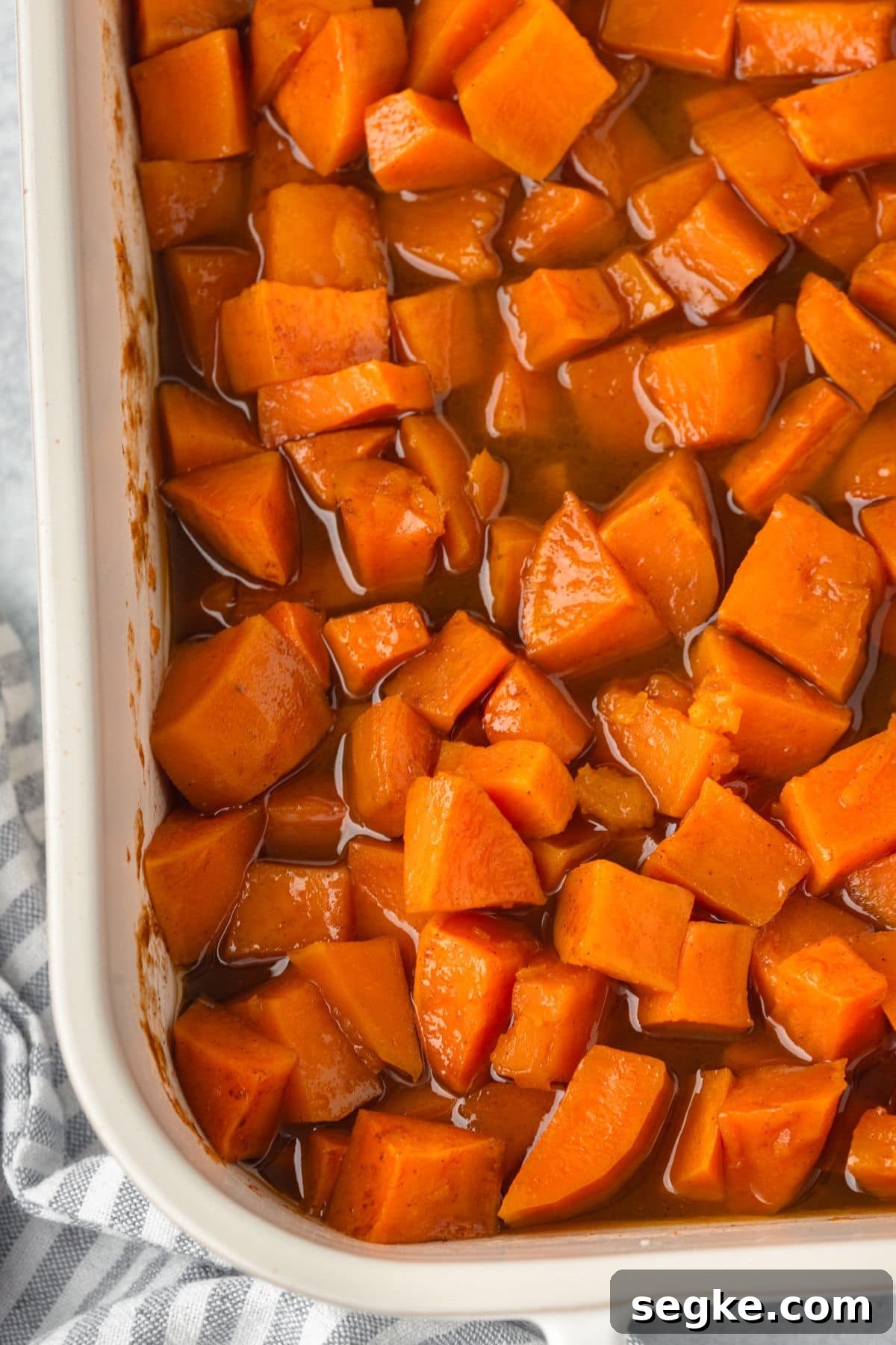 Candied Yams Recipe: Brown Sugar and Cinnamon Glaze 5 Sweet potato cubes in baking dish with caramelized glaze.