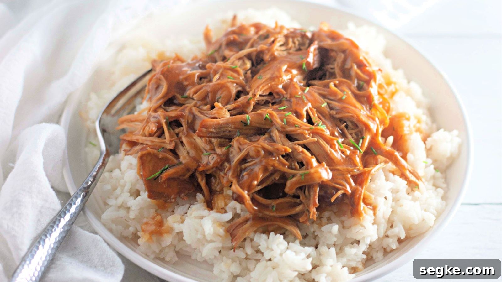 5-Ingredient Paleo Slow Cooker Chicken Recipe 9 Paleo honey garlic chicken shredded on white rice in a bowl.