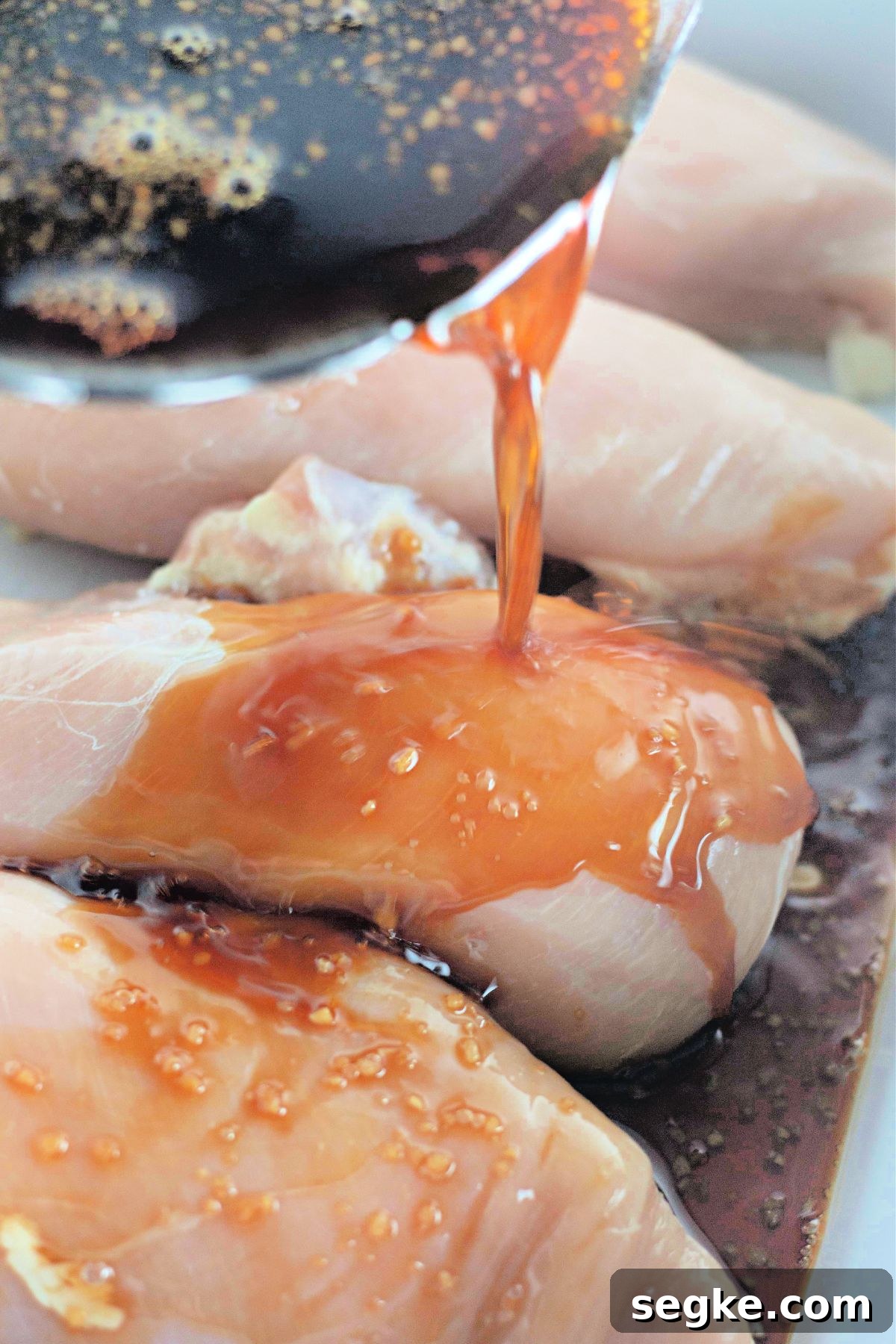 5-Ingredient Paleo Slow Cooker Chicken Recipe 4 Paleo honey garlic sauce being poured onto chicken breasts in a slow cooker.