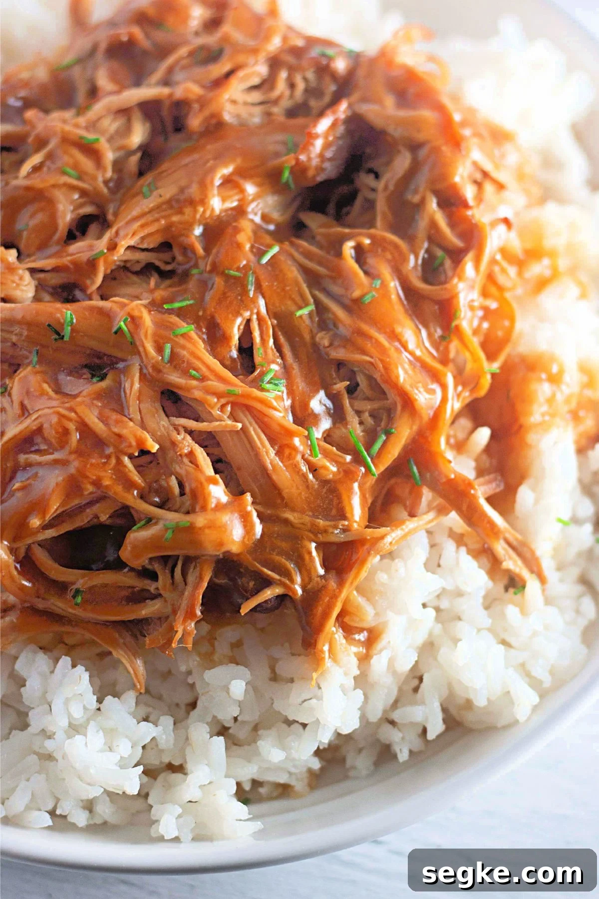 5-Ingredient Paleo Slow Cooker Chicken Recipe 8 Close up of paleo honey garlic chicken shredded on white rice in a bowl.