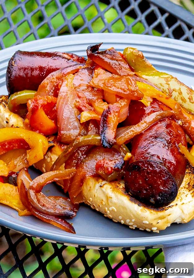 Grilled Sausage with Peppers and Onions Recipe 2 Grilled Sausage with Peppers and Onions on a bun on a gray plate