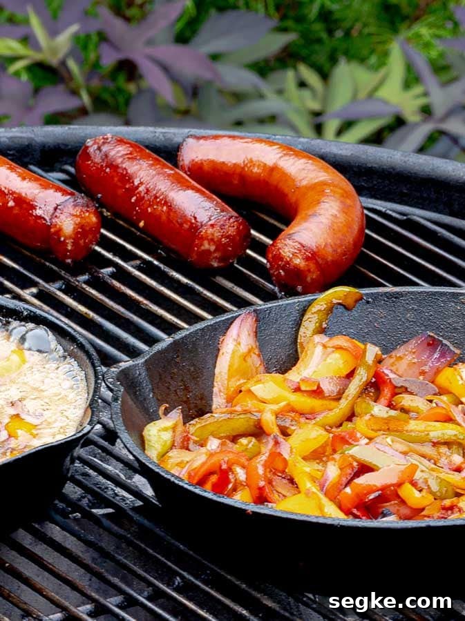 Grilled Sausage with Peppers and Onions Recipe 6 sausages and a cast iron skillet of onions and peppers on the grill