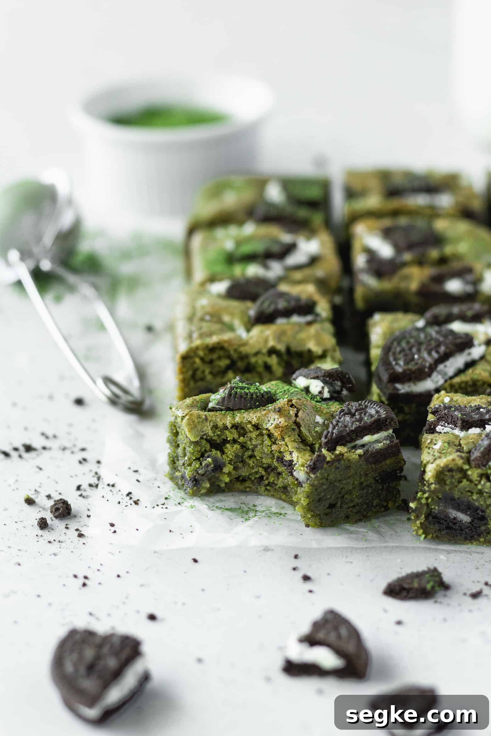 A bitten square of matcha blondie with Oreos