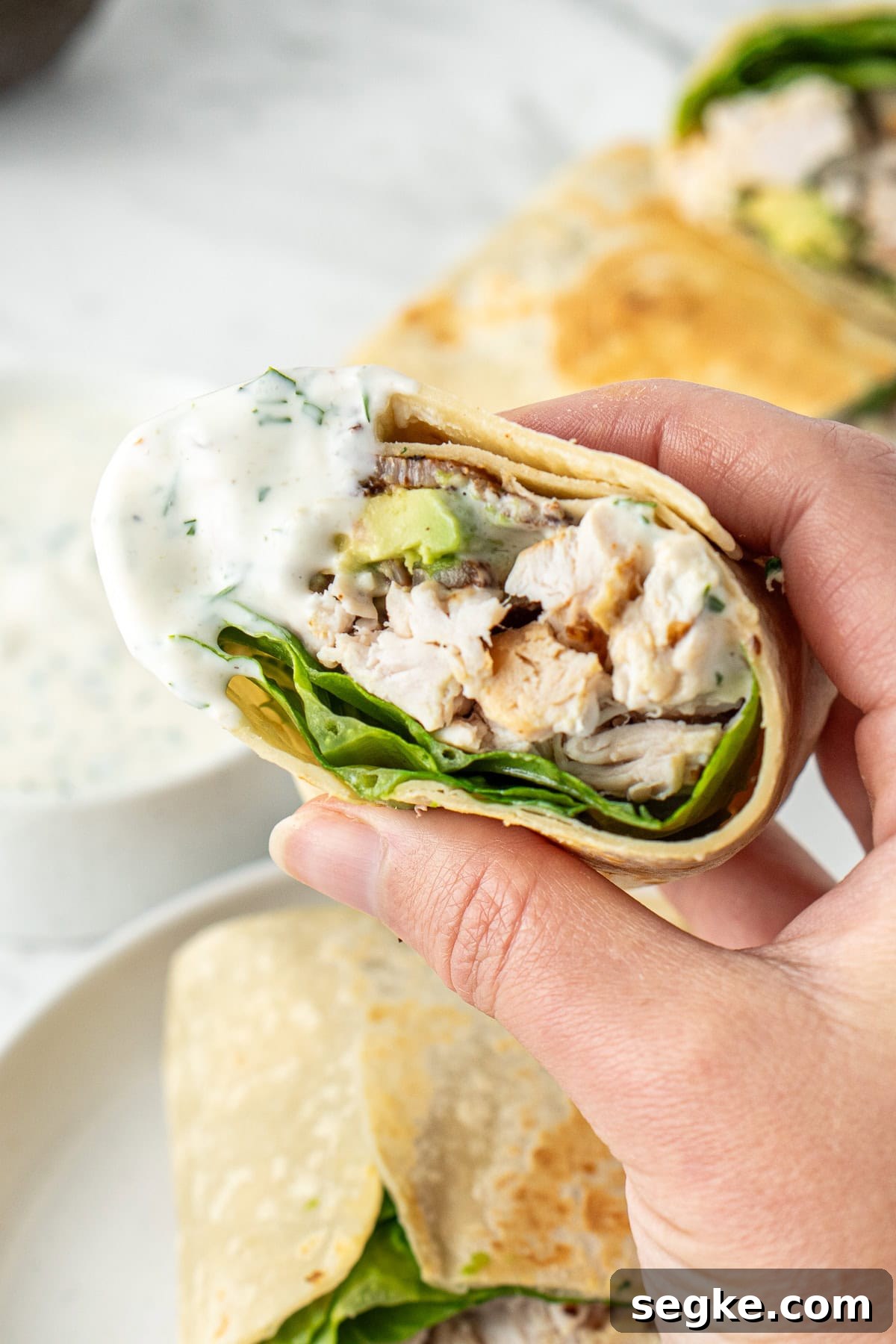 A hand holding a wrap dunked in ranch dressing.