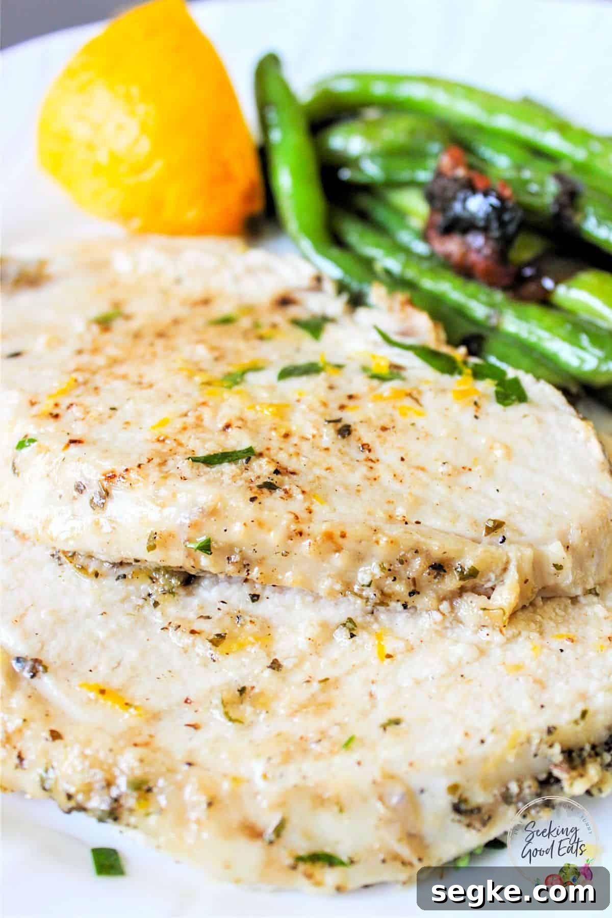 Juicy slices of slow cooker turkey breast on a white plate with a side green beans.