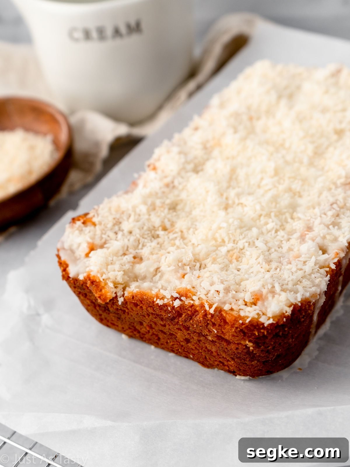 Moist Gluten-Free Coconut Cake Recipe 11 Loaf cake topped with icing and shredded coconut.