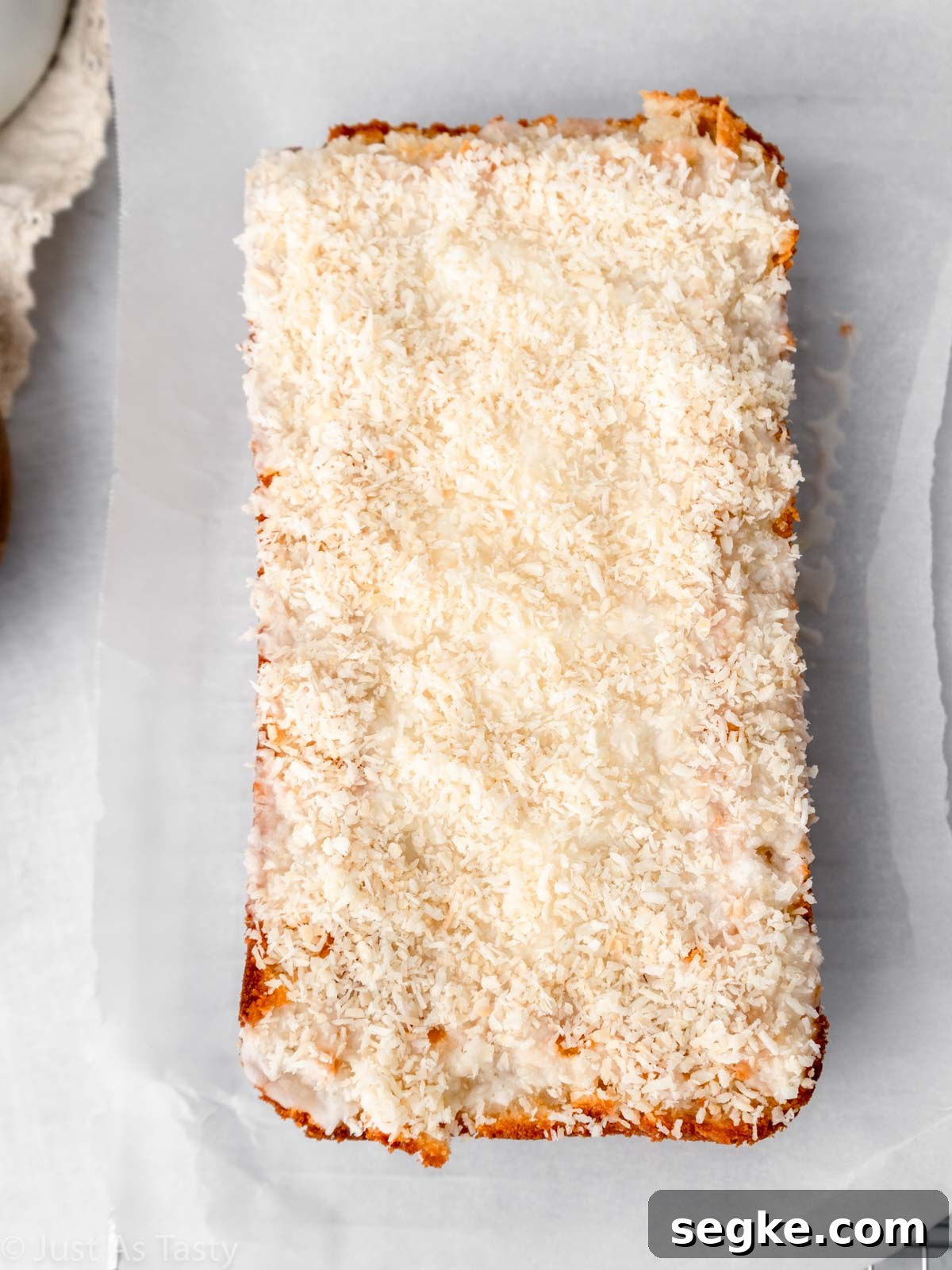 Moist Gluten-Free Coconut Cake Recipe 3 Loaf cake topped with icing and shredded coconut.
