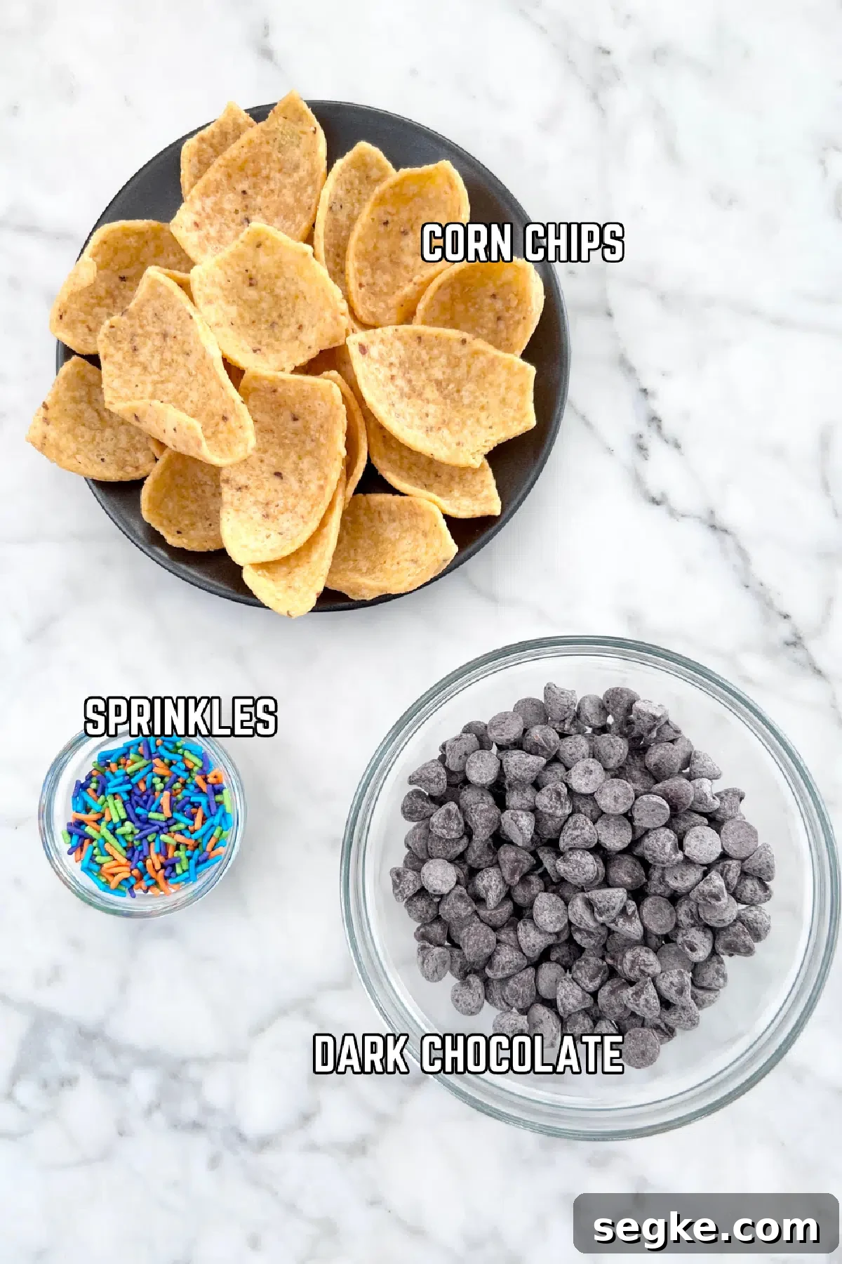 Three bowls of ingredients to make chocolate dipped corn chips: chips, dark chocolate, and colorful sprinkles.
