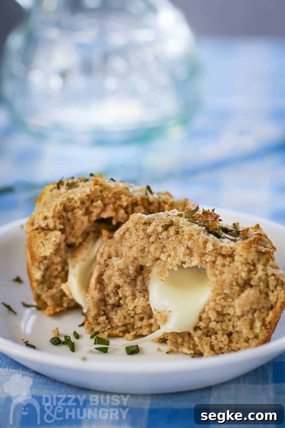 Flaky Mozzarella-Stuffed Whole-Wheat Biscuits Recipe 2 Side shot of a biscuit split in half with mozzarella inside garnished with fresh herbs on a white plate.