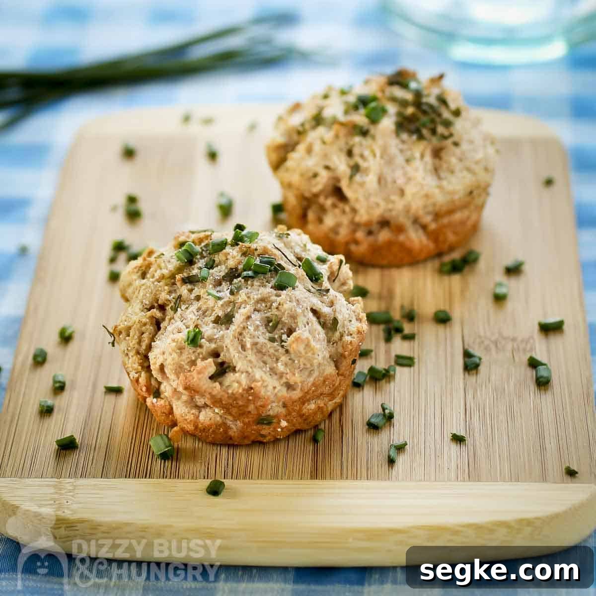 Flaky Mozzarella-Stuffed Whole-Wheat Biscuits Recipe 9 Side shot of two biscuits garnished with fresh chives on a wooden cutting board on a blue plaid cloth.