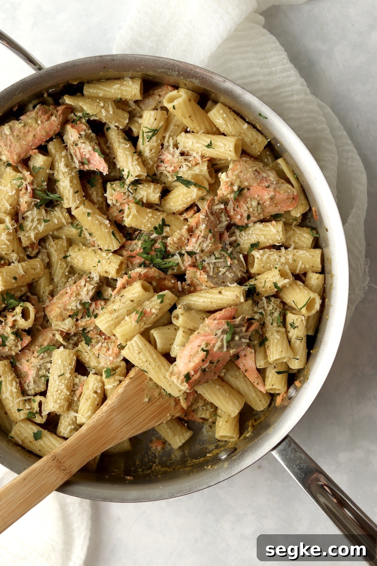 salmon pesto pasta in pan with wooden spoon