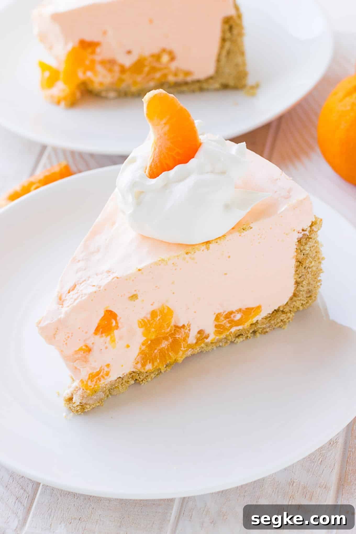 A slice of orange pie on a plate showing the orange orange segments and creamy filling in each slice.