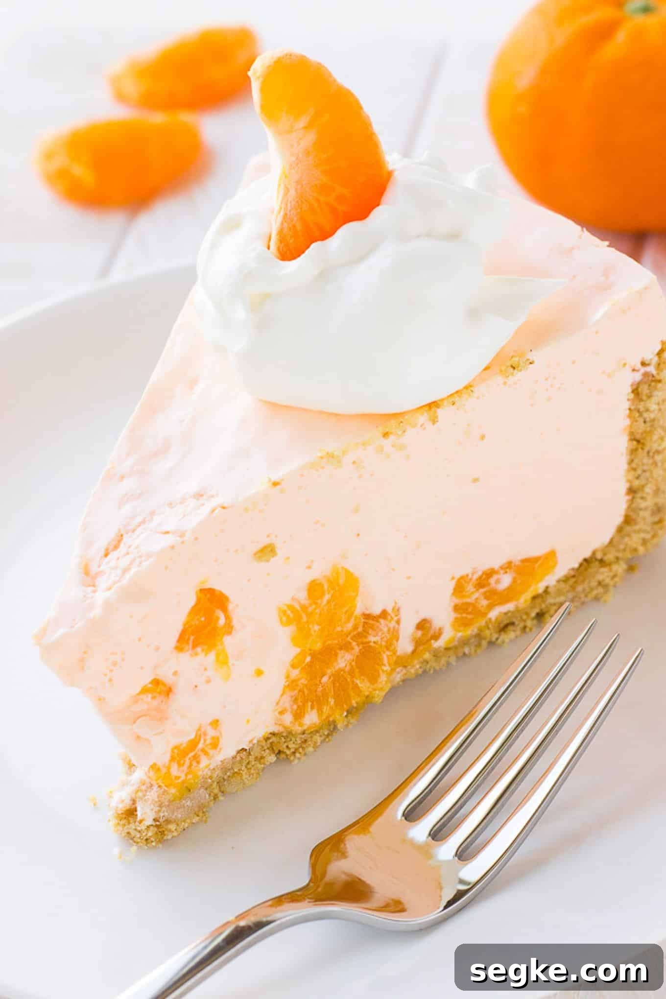 A slice of orange cream pie on a plate with a fork.