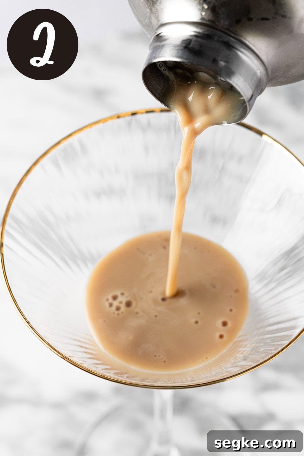 Pouring the gingerbread martini from the cocktail shaker into the martini glass.
