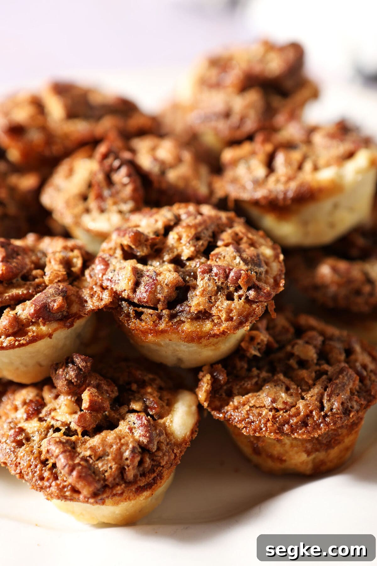 a stack of pecan tassie cookies on a white platter