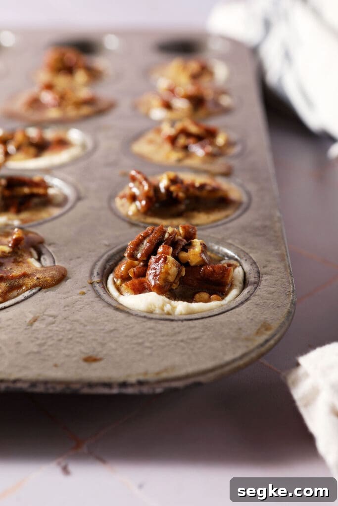 pecan pie filling sits on top of mini muffin cups in a mini muffin tin before baking