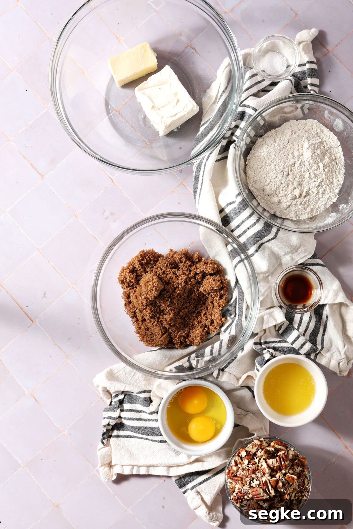ingredients to make pecan tassies in bowls on a purple surface with a white and black striped towel