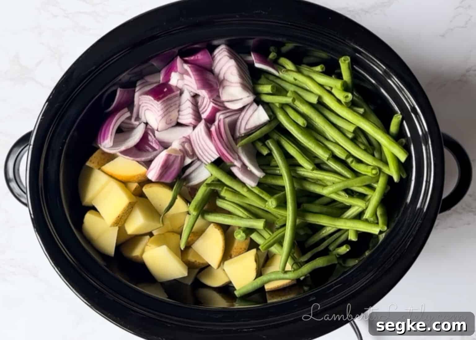 Slow Cooker Southern Swamp Potatoes Recipe 6 chopped potatoes, red onion, and green beans in a slow cooker.