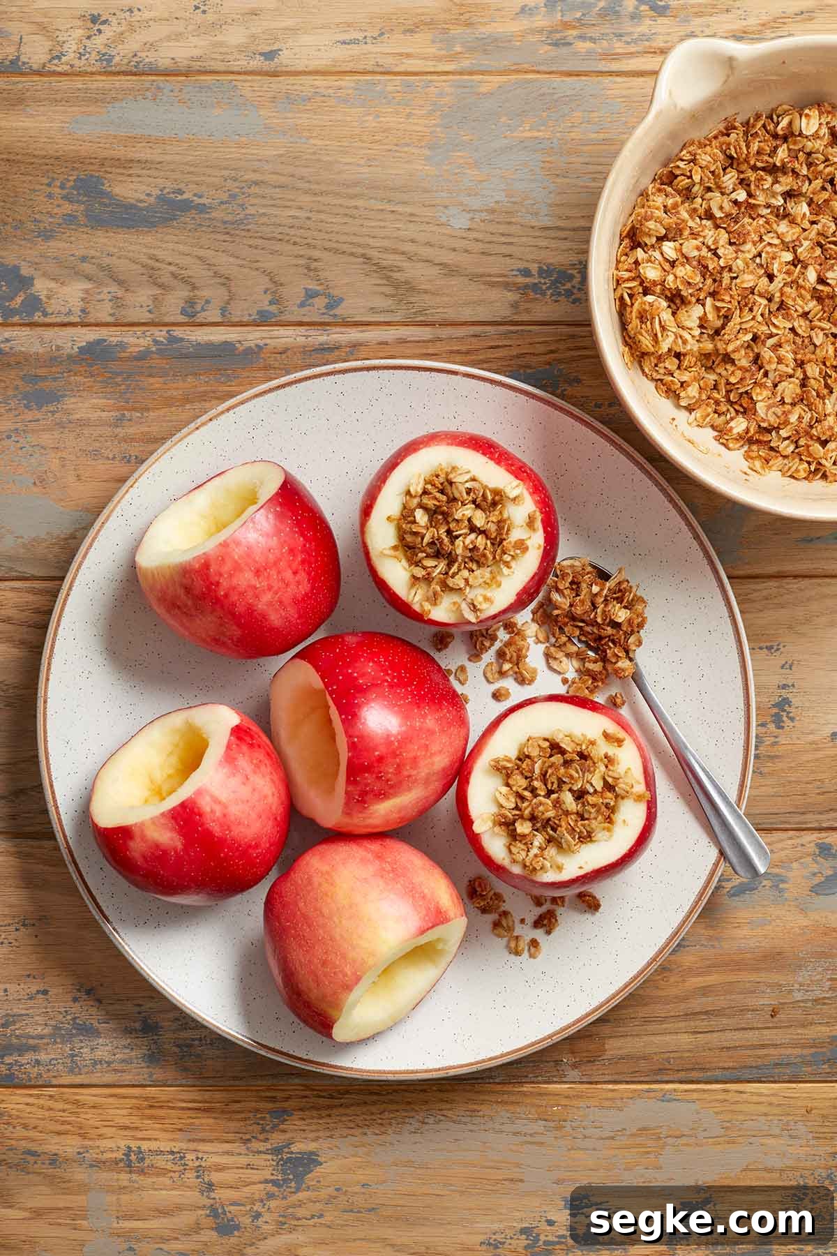 Cored apples on a plate and being filled with oat mixture.