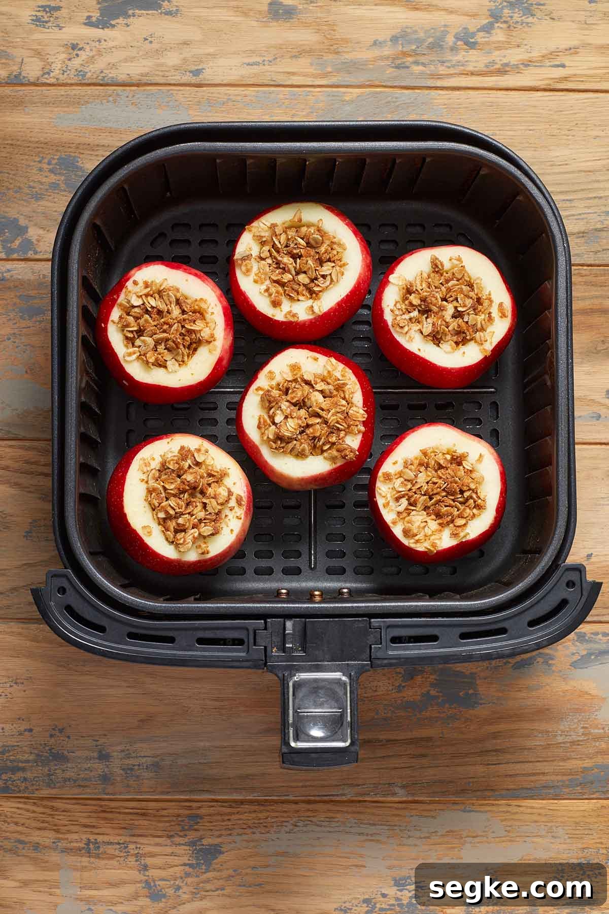 Pre-cooked stuffed apples in the air fryer basket.